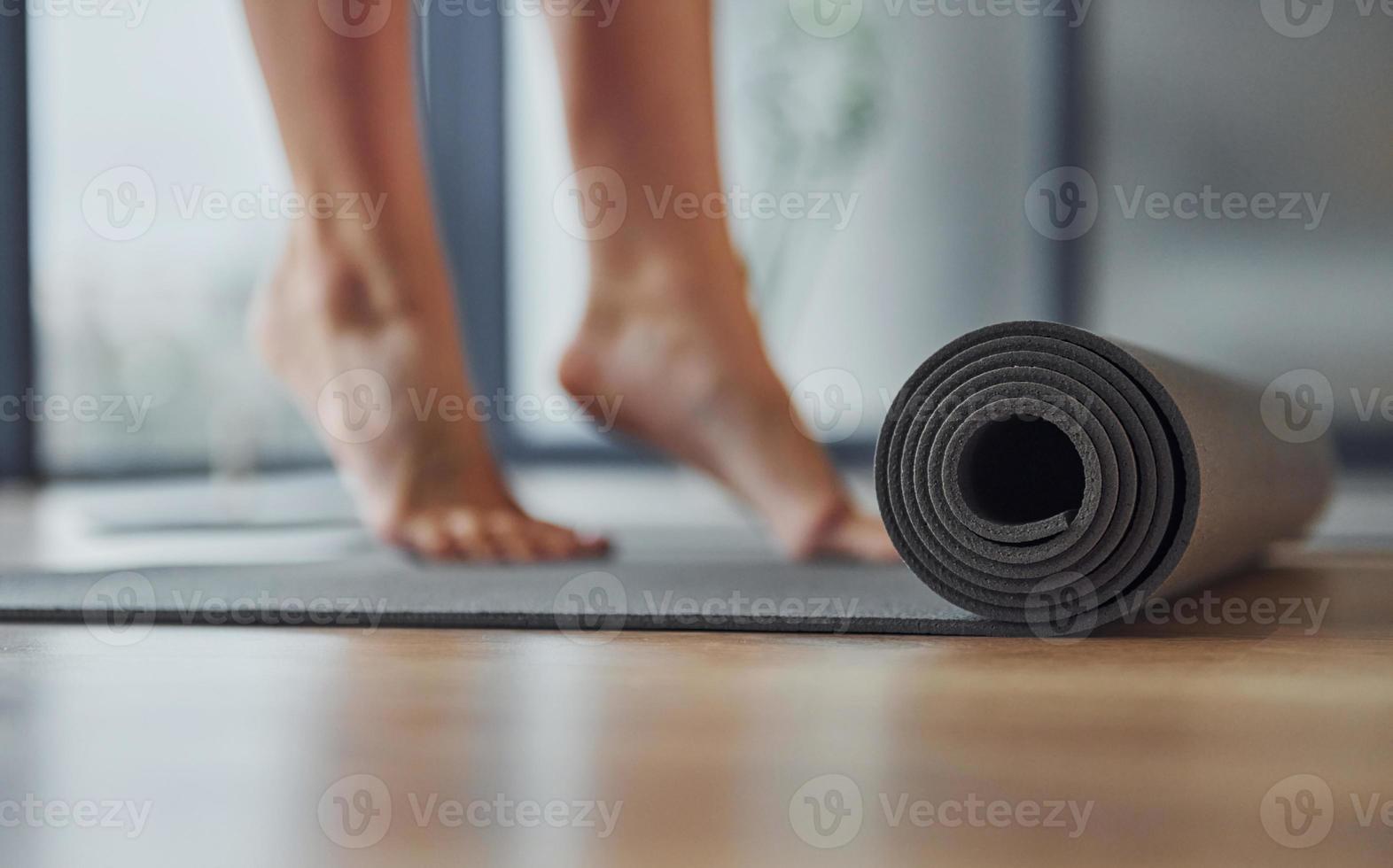 vicino su focalizzata Visualizza su stuoia. giovane donna nel allegro indossare e con sottile corpo avere fitness yoga giorno in casa foto