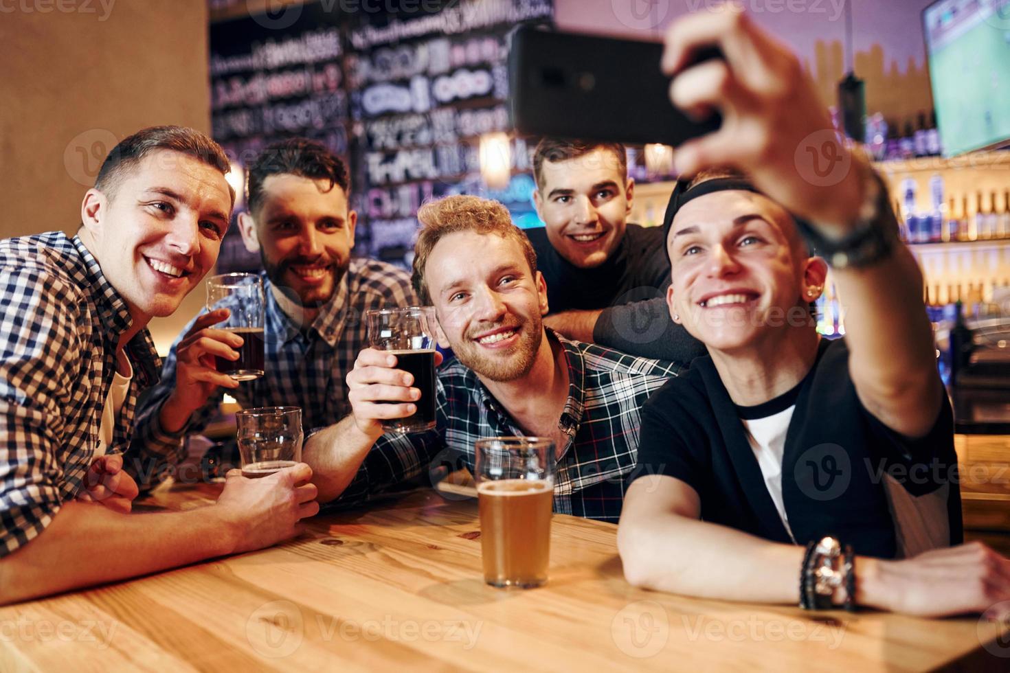 uomo prende autoscatto di Telefono. gruppo di persone insieme in casa nel il pub avere divertimento a fine settimana tempo foto