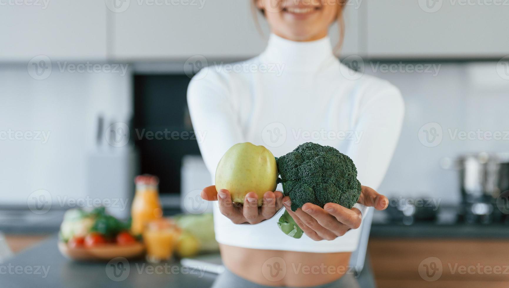 pose per un' telecamera con verdure. giovane europeo donna è in casa a cucina in casa con salutare cibo foto