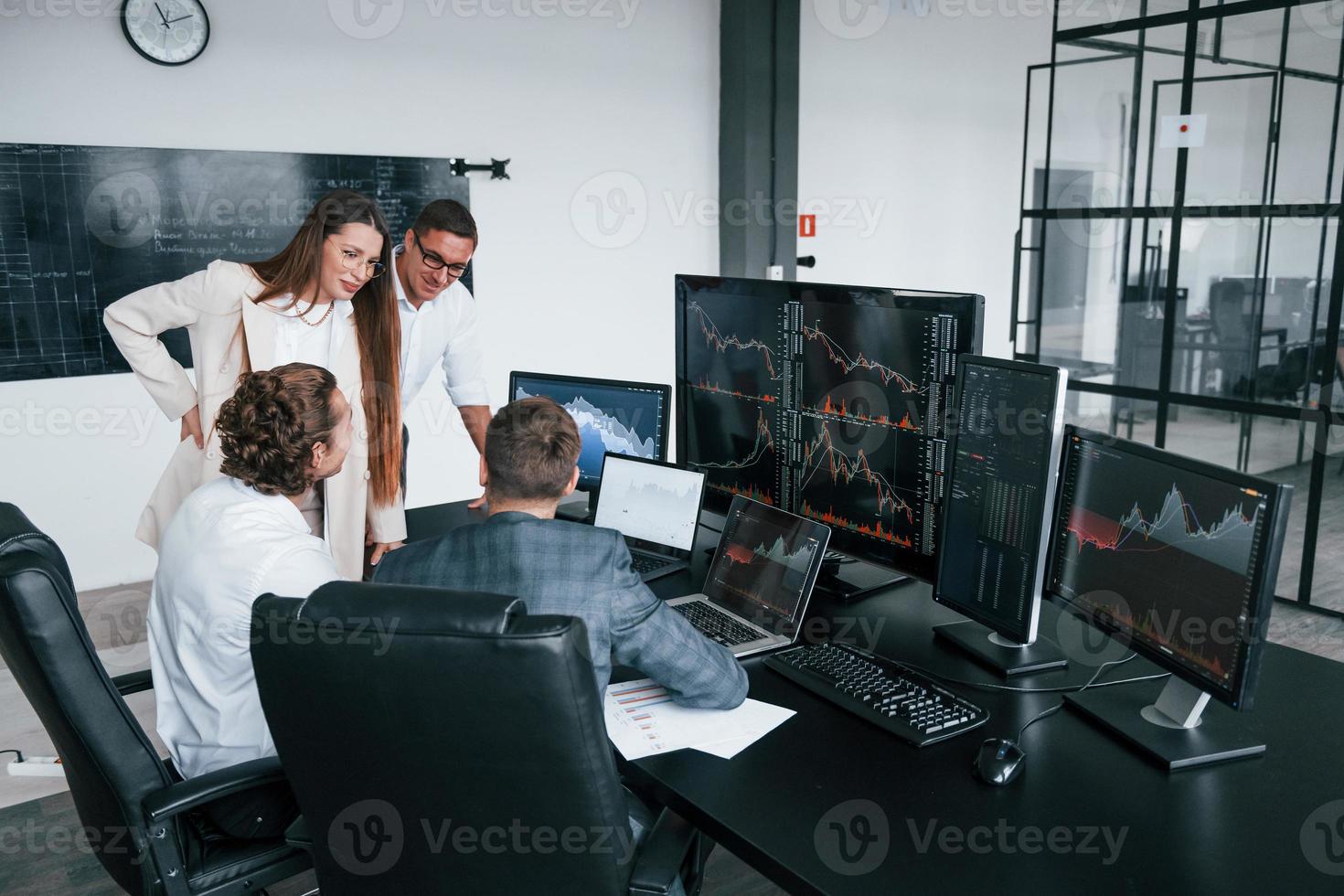 Attenzione per particolari. squadra di agenti di cambio lavori nel moderno ufficio con molti Schermo schermi foto