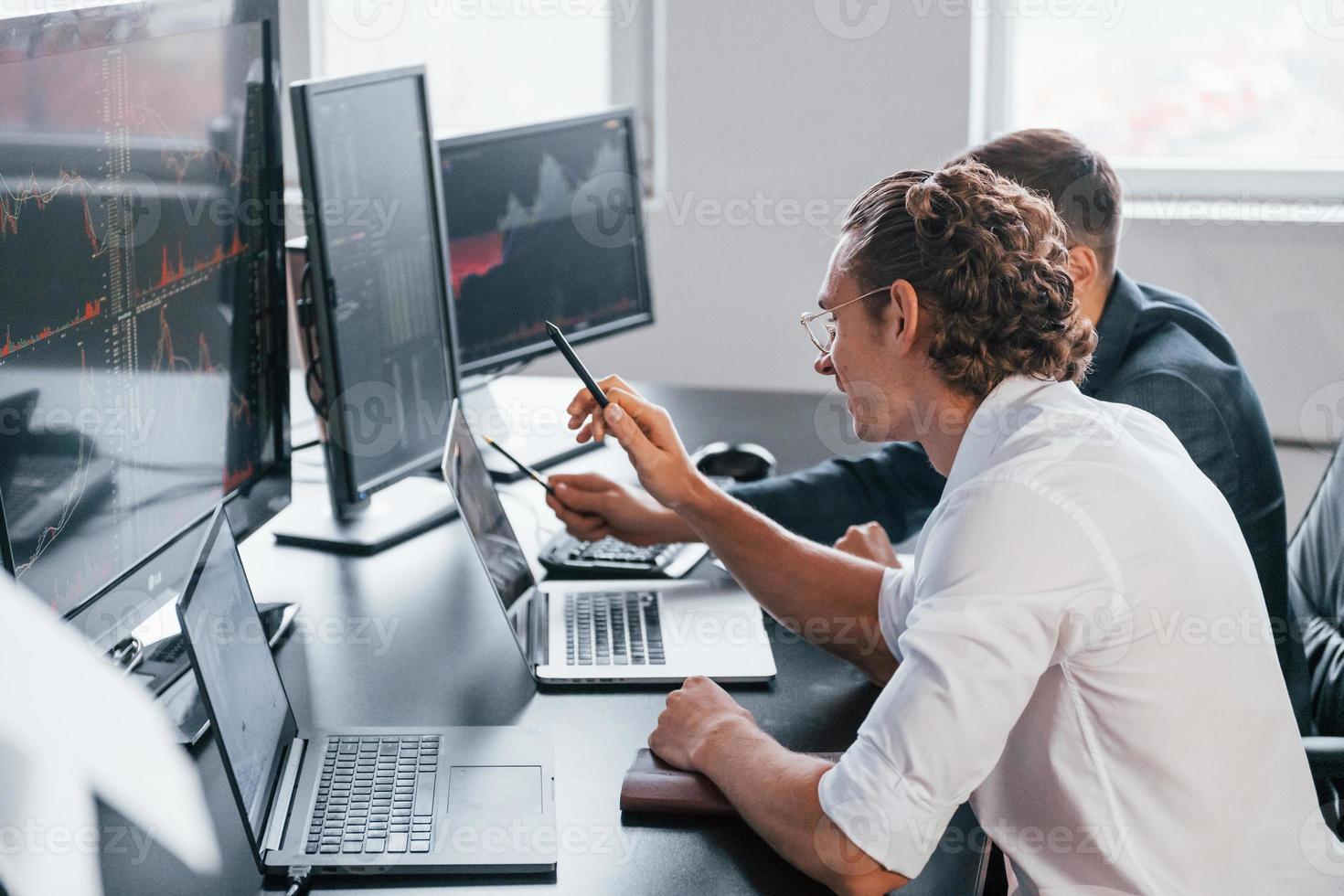 Attenzione per particolari. squadra di agenti di cambio lavori nel moderno ufficio con molti Schermo schermi foto