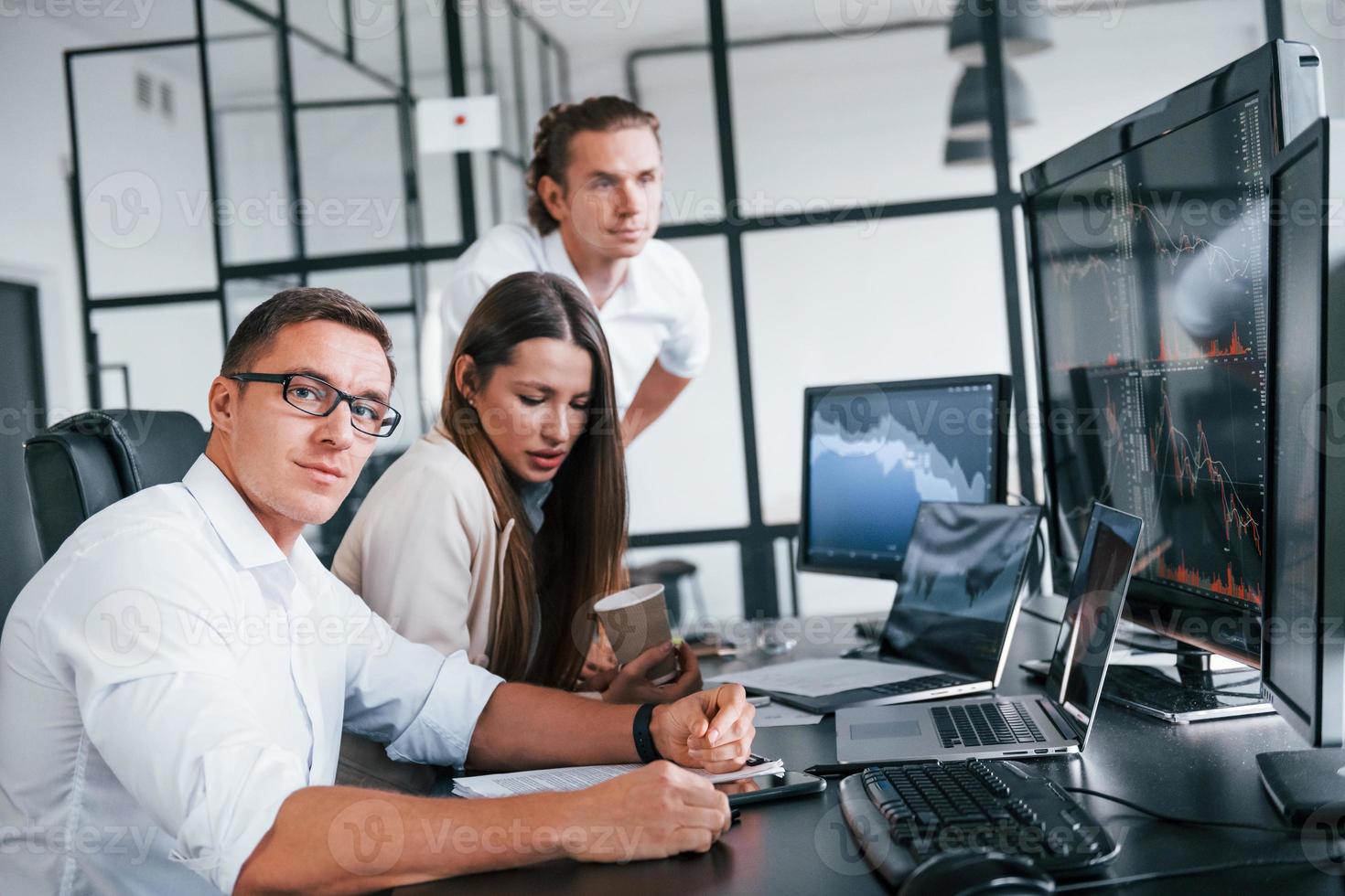 analizzando informazione. squadra di agenti di cambio lavori nel moderno ufficio con molti Schermo schermi foto