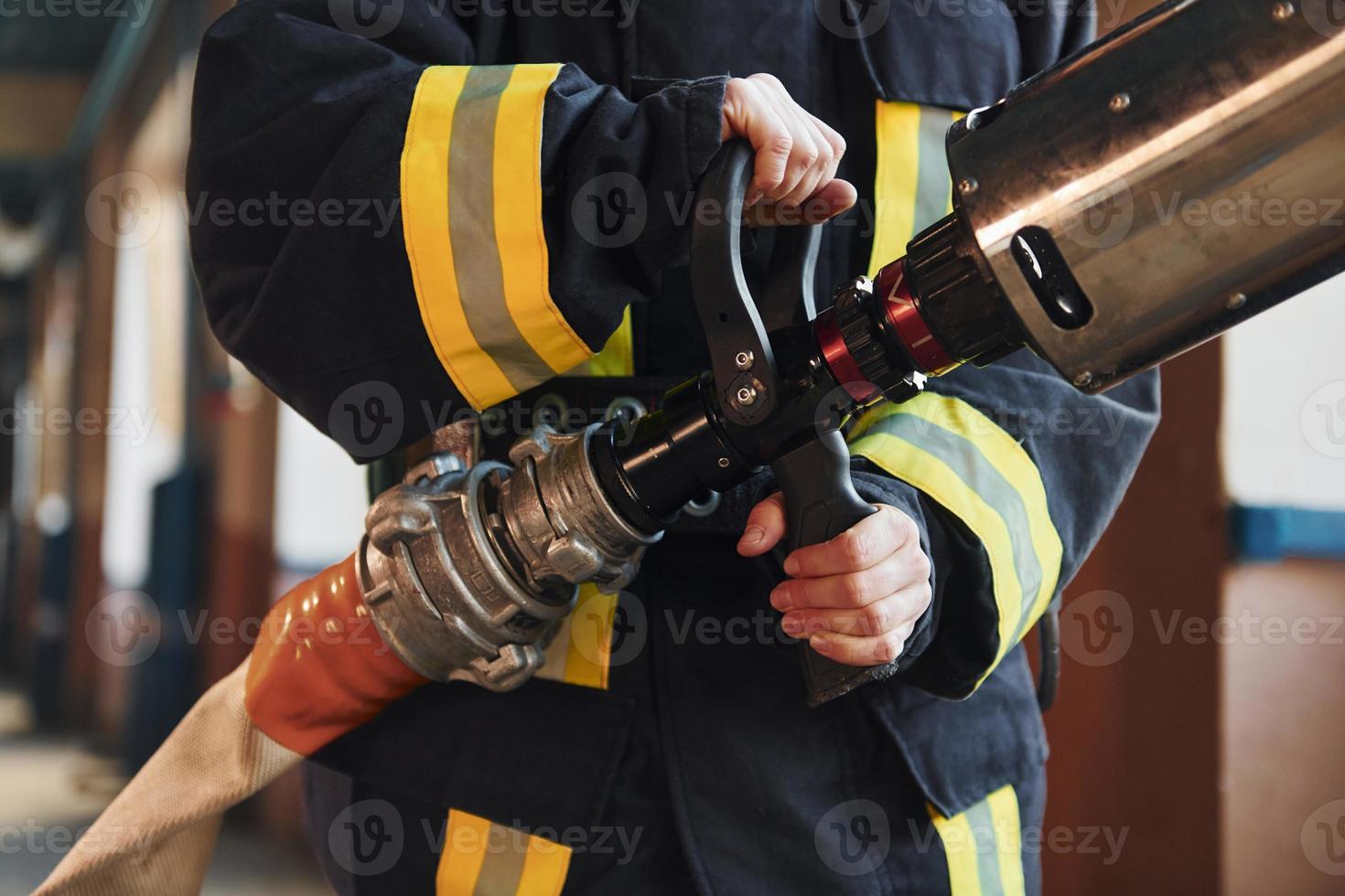 tubo flessibile nel mani. femmina pompiere nel protettivo uniforme in piedi vicino camion foto