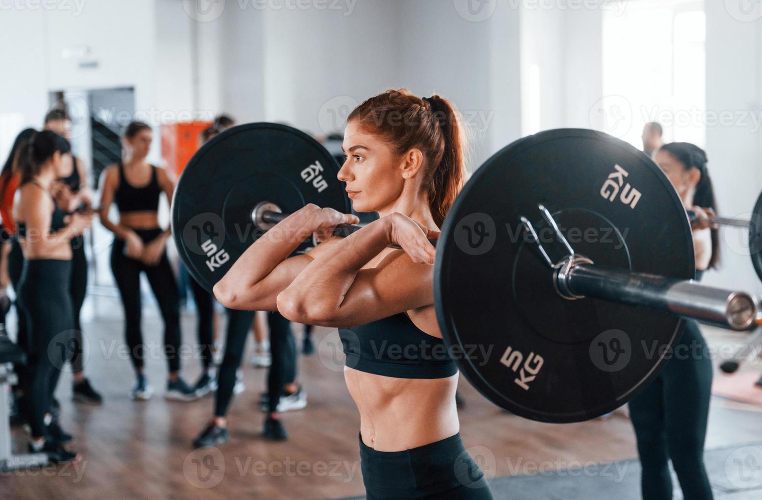 squat con bilanciere. gruppo di giovane allegro persone avere CrossFit giorno in casa nel Palestra foto