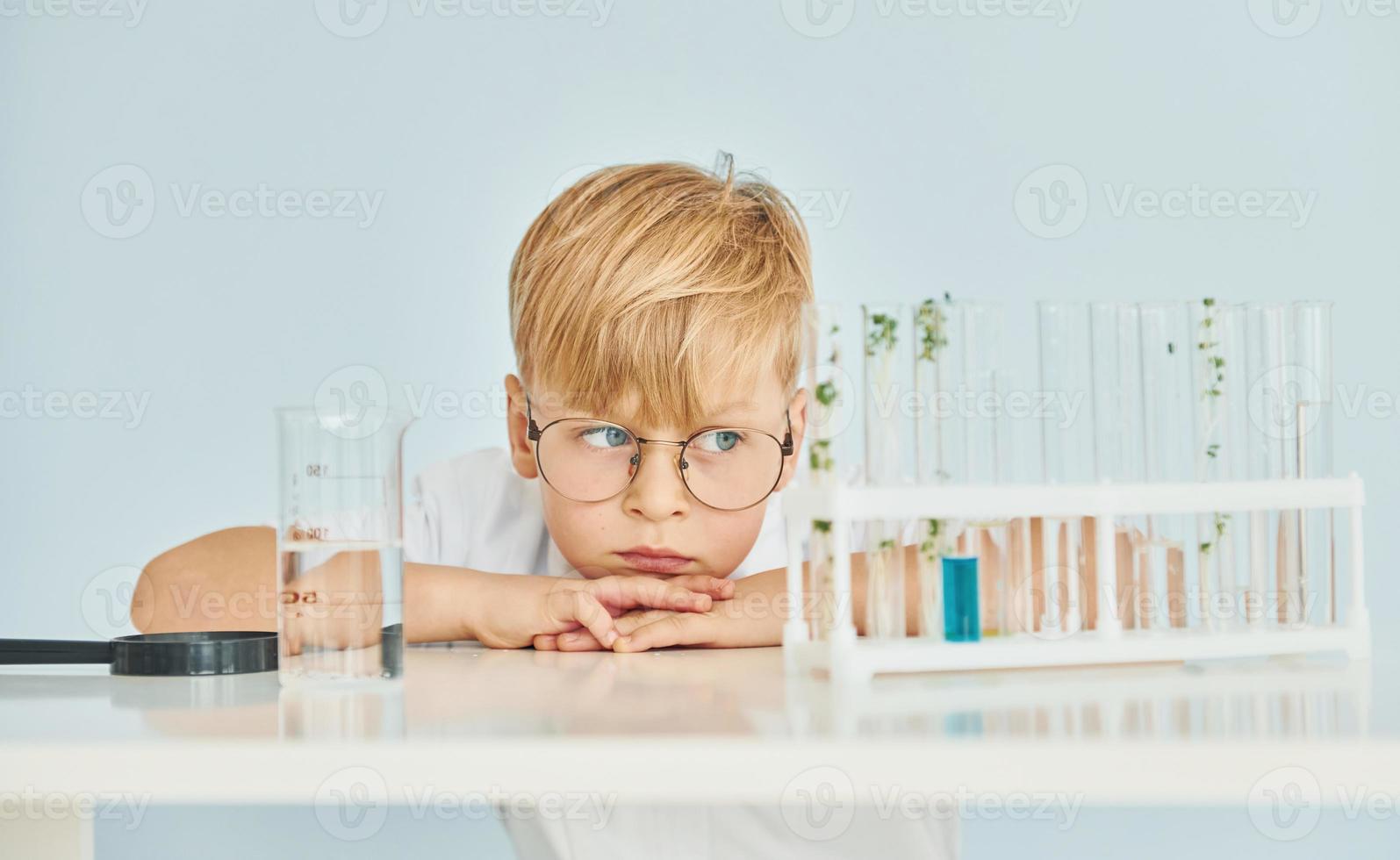 usi test tubi. poco ragazzo nel cappotto giocando un' scienziato nel laboratorio di utilizzando attrezzatura foto