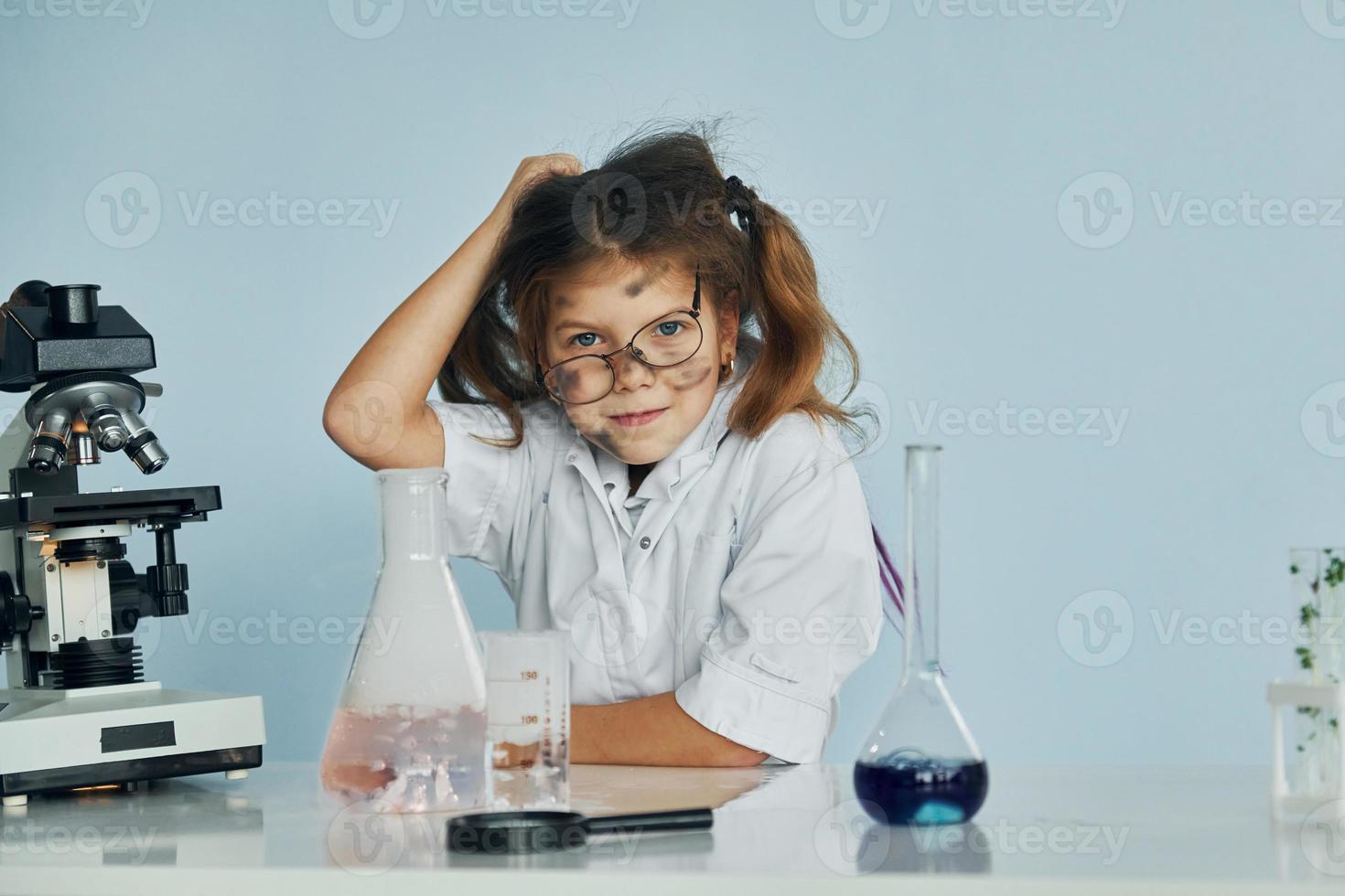 senza esito sperimentare. poco ragazza nel cappotto giocando un' scienziato nel laboratorio di utilizzando attrezzatura foto