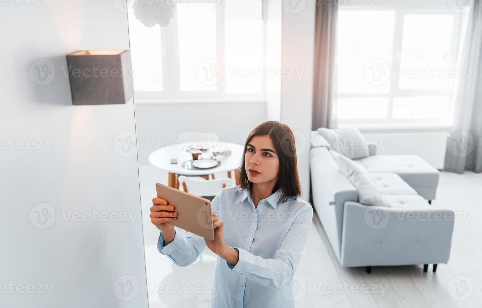 commutazione il illuminazione. giovane donna è in casa nel inteligente Casa camera a giorno foto