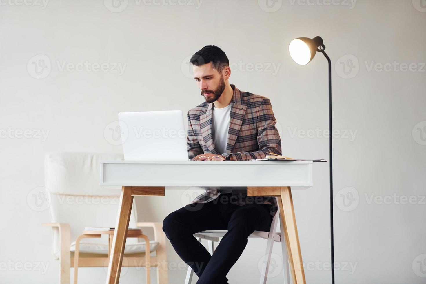 usi il computer portatile. giovane elegante uomo d'affari nel completo da uomo al chiuso. concezione di successo foto