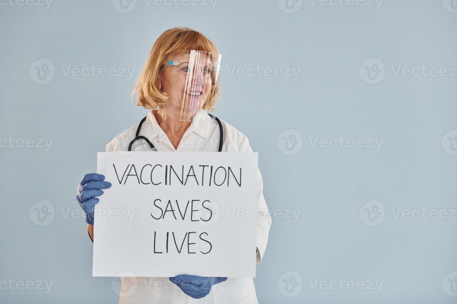 vaccinazione salva vite striscione. anziano femmina medico nel bianca cappotto è in piedi in casa foto