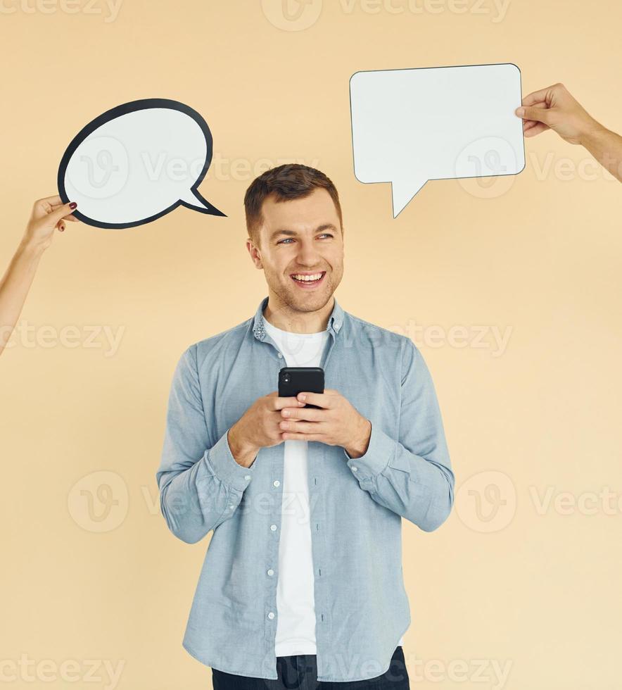 Tenere smartphone. molti idee. uomo in piedi nel il studio con vuoto segni per il testo foto