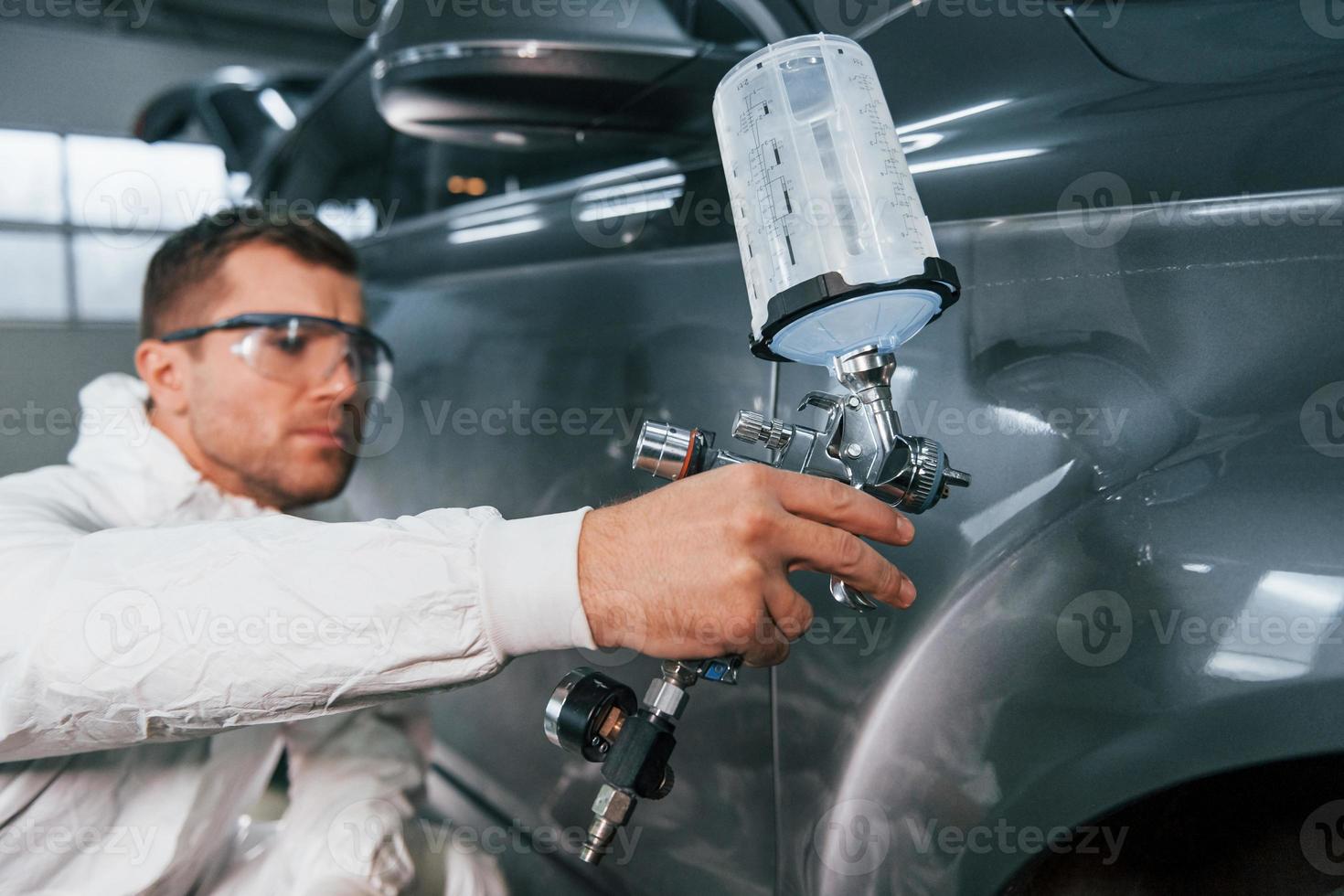 processi di pittura il macchina. uomo nel uniforme è Lavorando nel il auto servizio foto