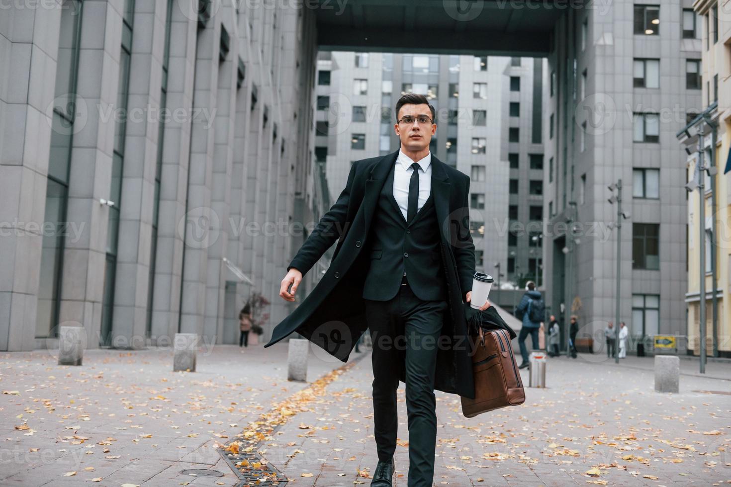 andando per opera. uomo d'affari nel nero completo da uomo e cravatta è all'aperto nel il città foto