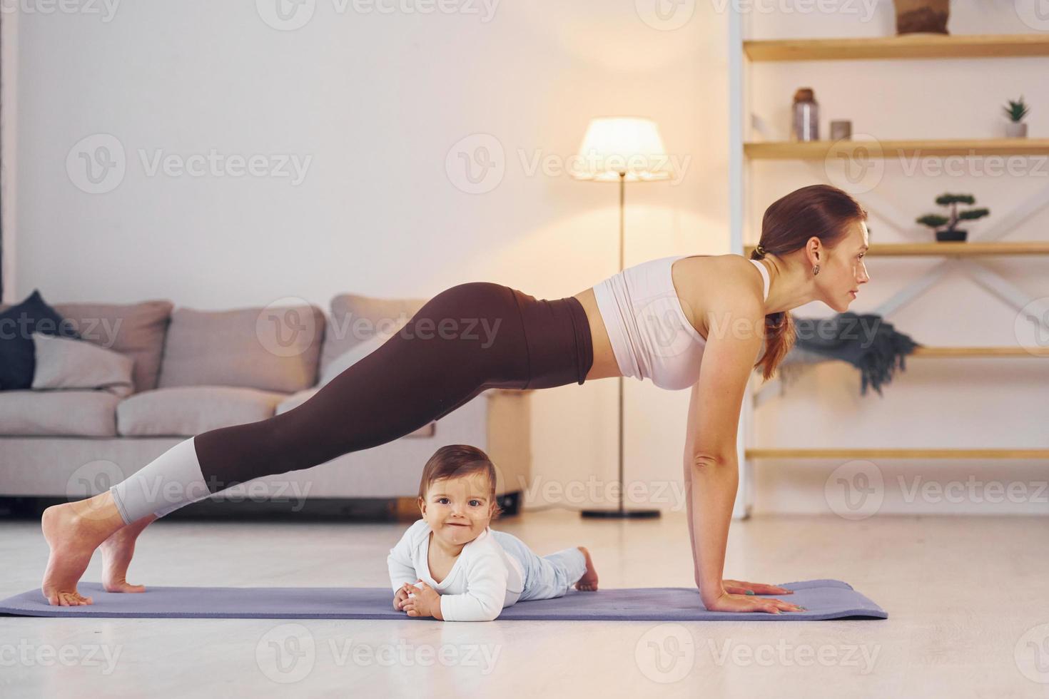 focalizzata a yoga esercizi. madre con sua poco figlia è a casa insieme foto