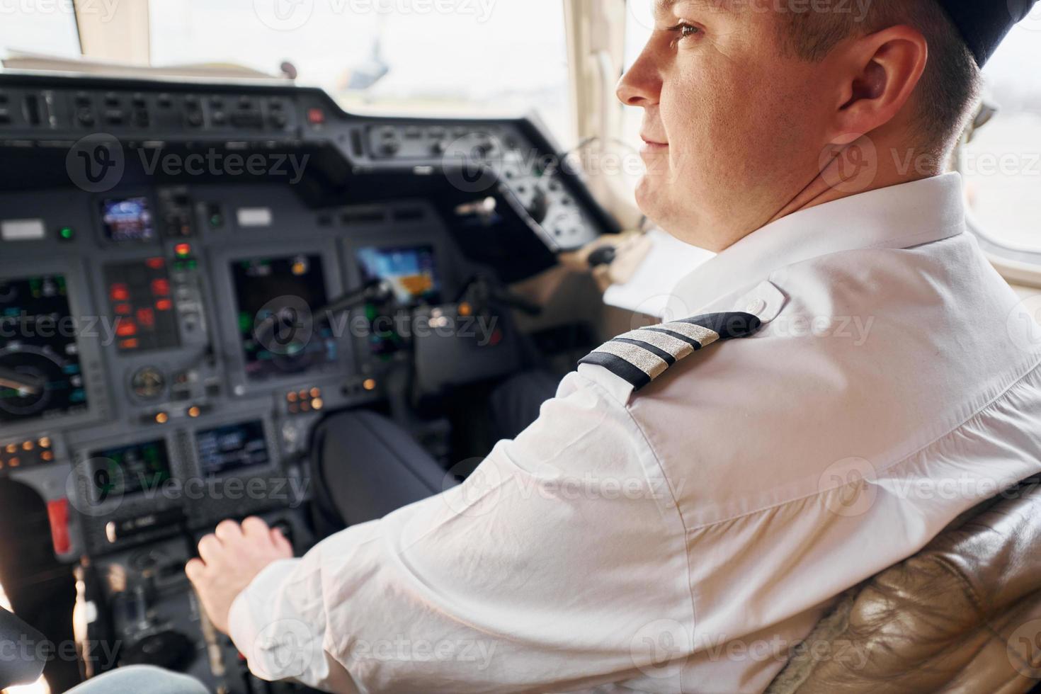 calma atmosfera. pilota nel formale indossare si siede nel il cabina di pilotaggio e controlli aereo foto