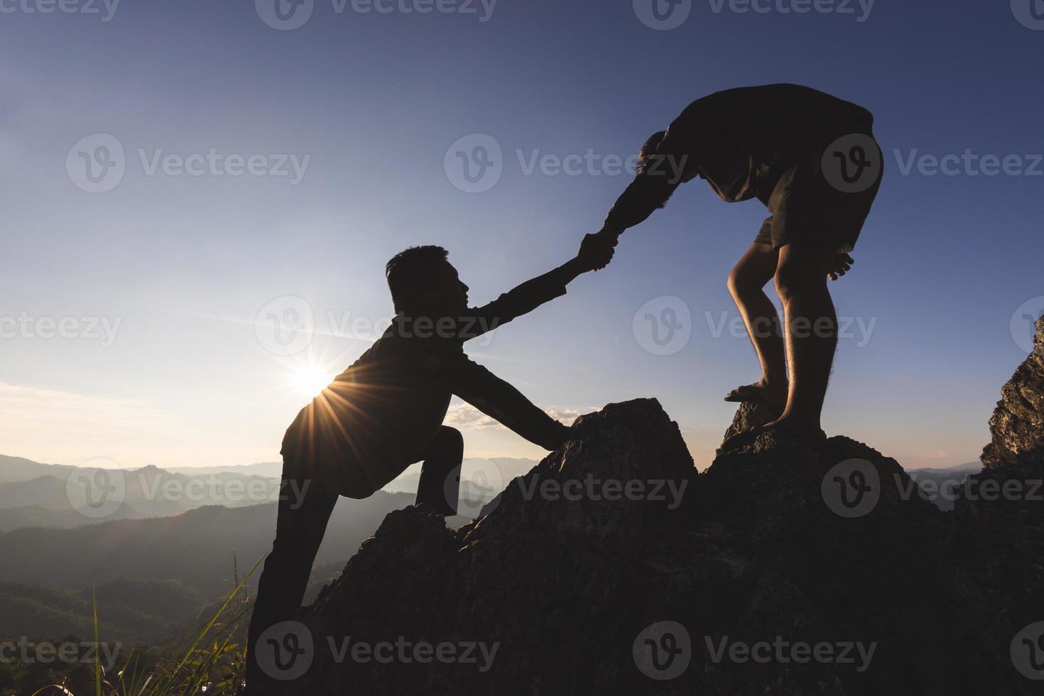 silhouette di il uomini porzione Tirare persone su a partire dal alto scogliere. foto