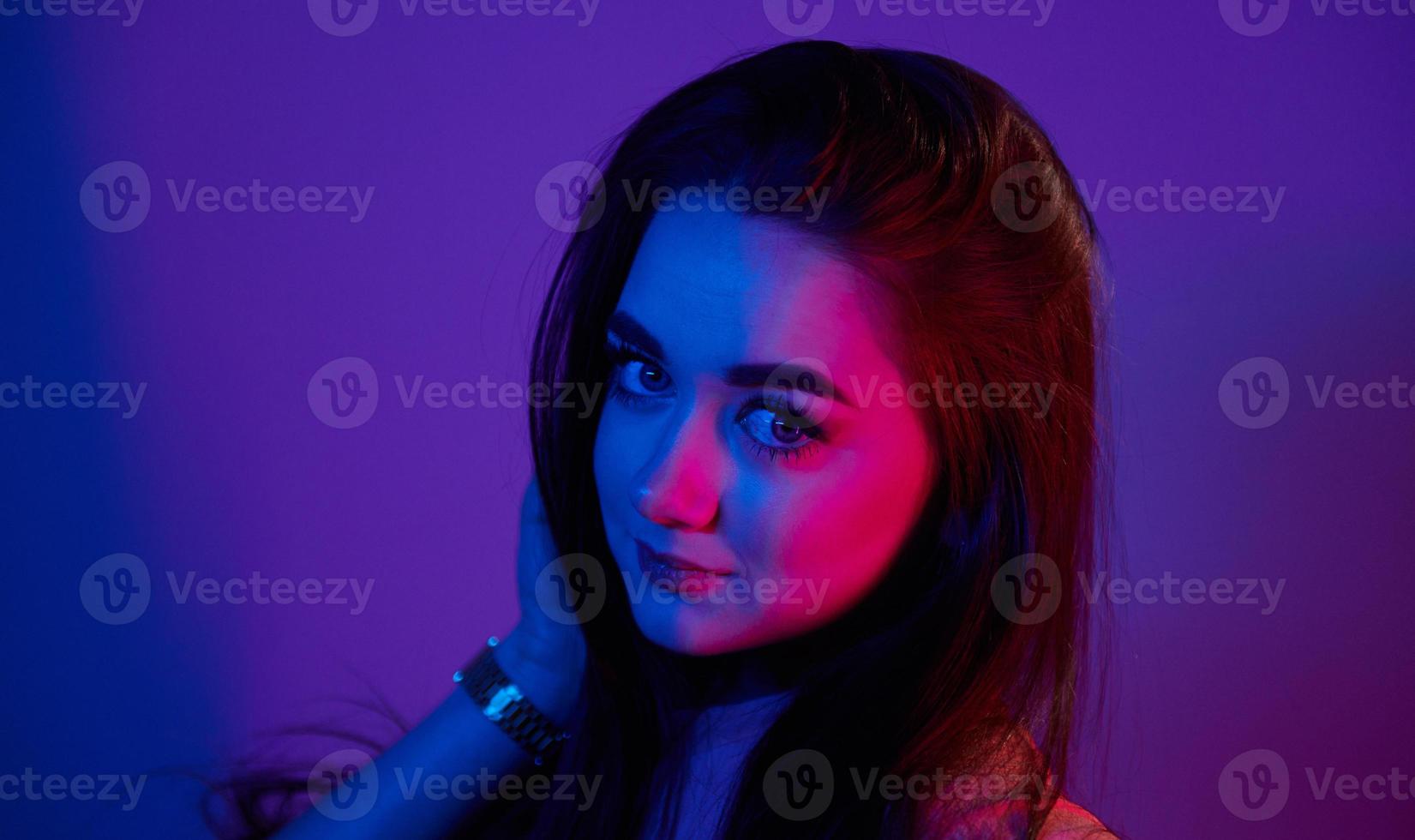 ritratto di alla moda giovane donna quello in piedi nel il studio con neon leggero foto