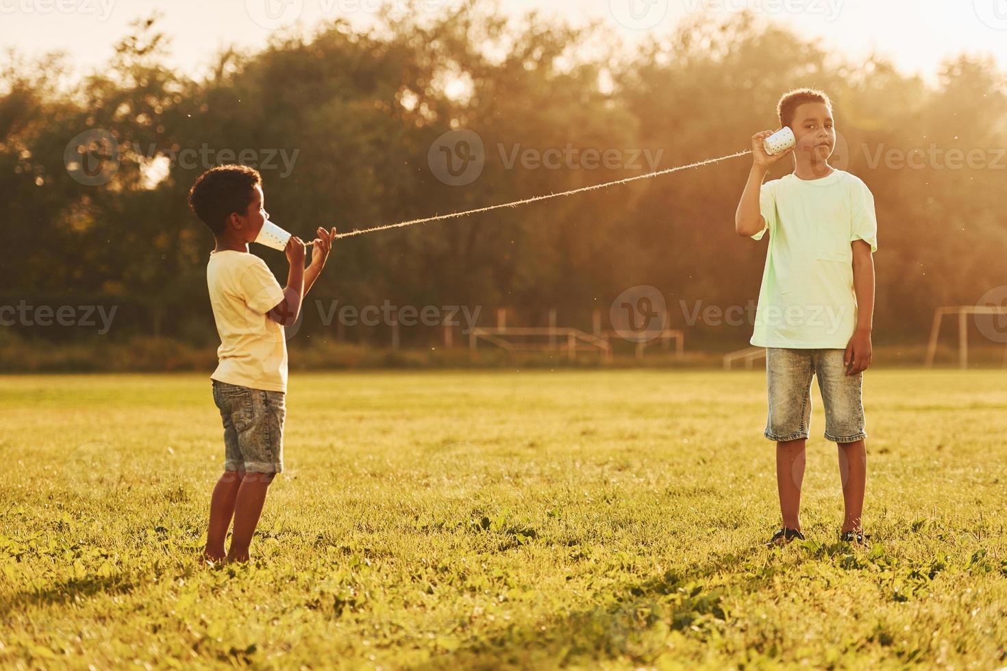 vecchio giocattolo Telefono. Due africano americano bambini avere divertimento nel il campo a estate giorno insieme foto