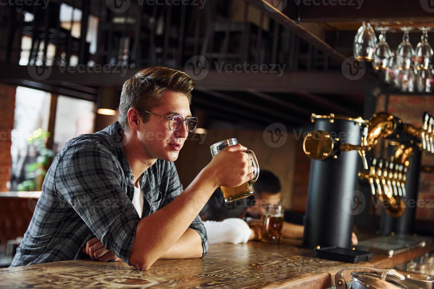 con birra. uomo nel casuale Abiti seduta nel il pub foto