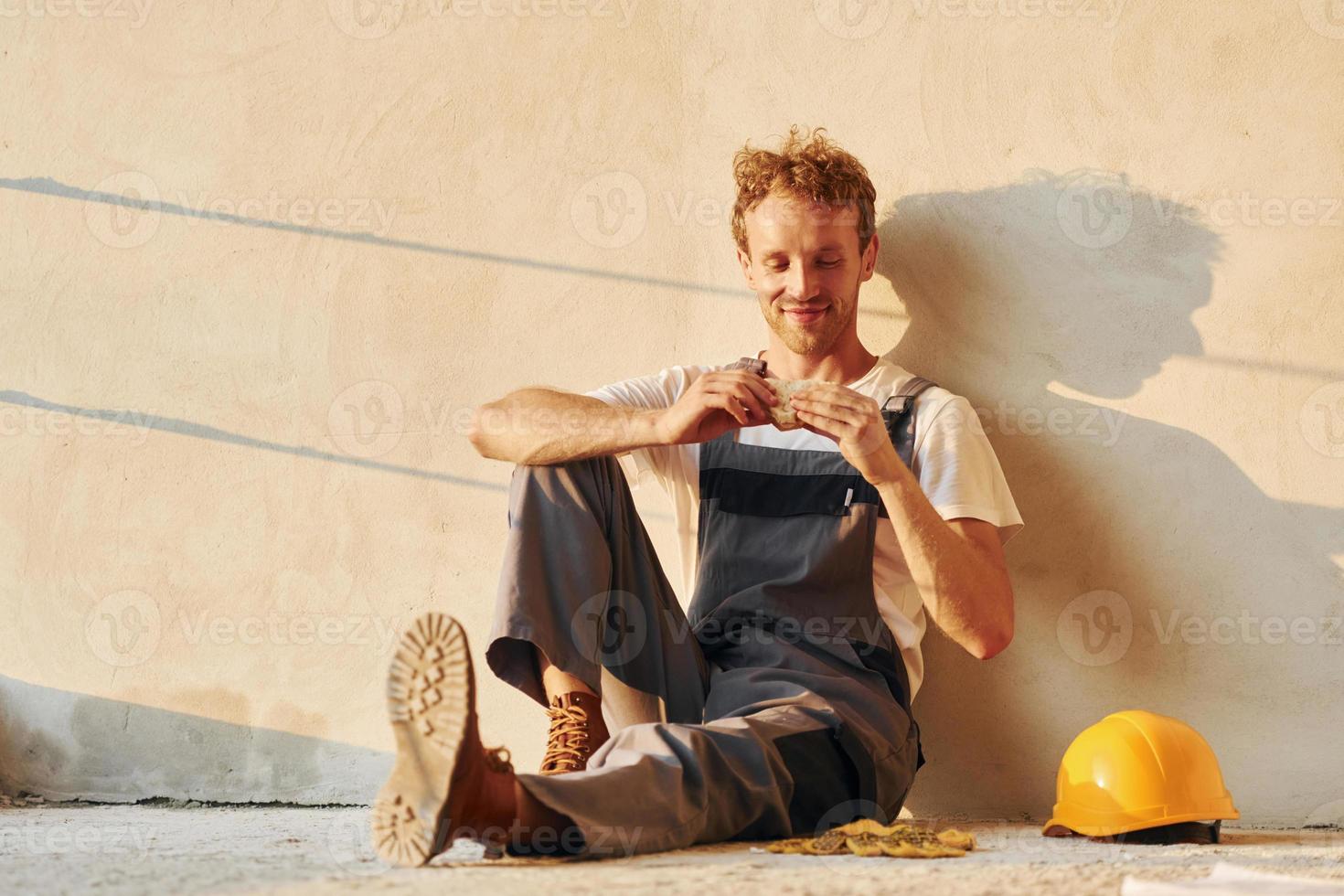 mangiare cibo. giovane uomo Lavorando nel uniforme a costruzione a giorno foto