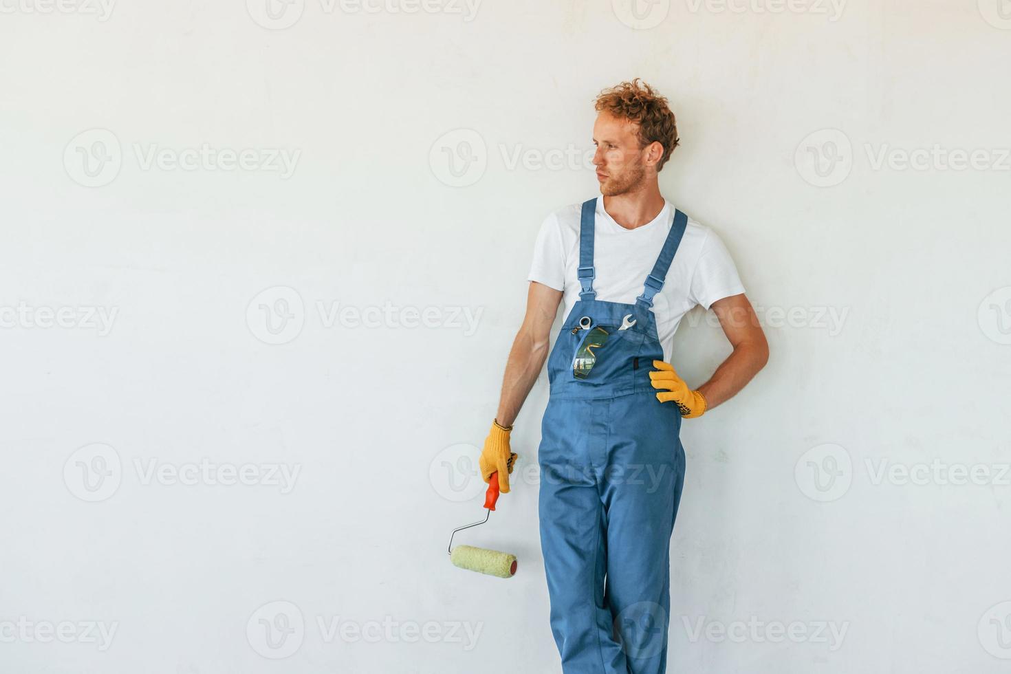 contro bianca muri. giovane uomo Lavorando nel uniforme a costruzione a giorno foto