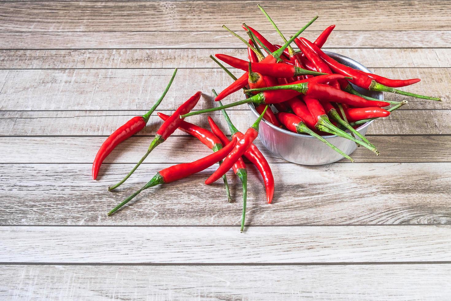 peperoncino rosso in una ciotola su un tavolo di legno foto