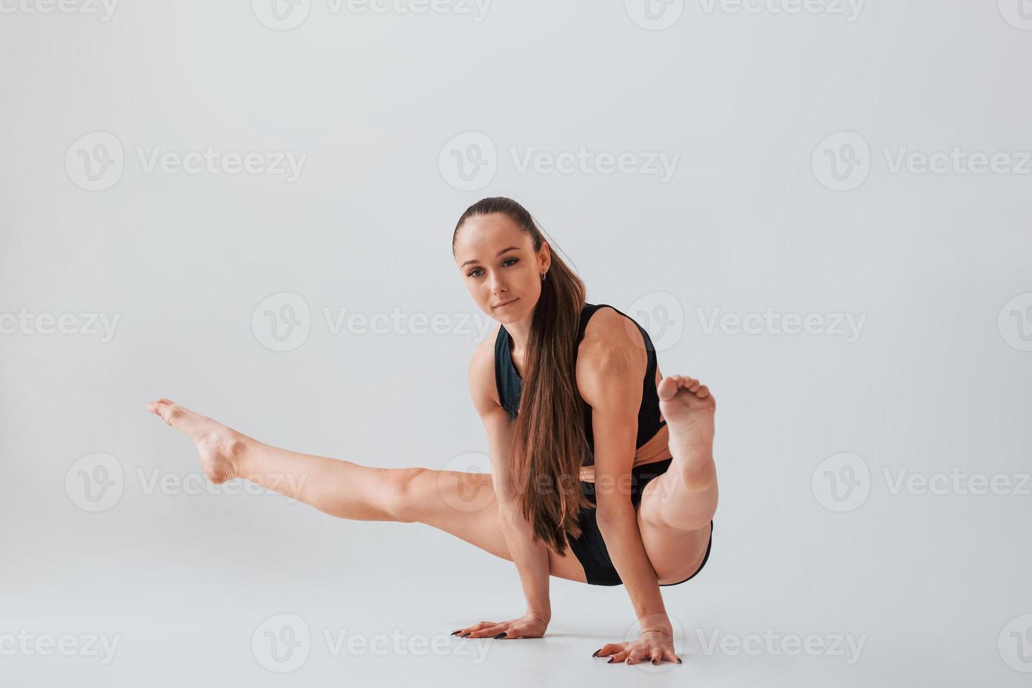 in piedi su il mani. giovane donna nel allegro Abiti fare ginnastica in casa foto