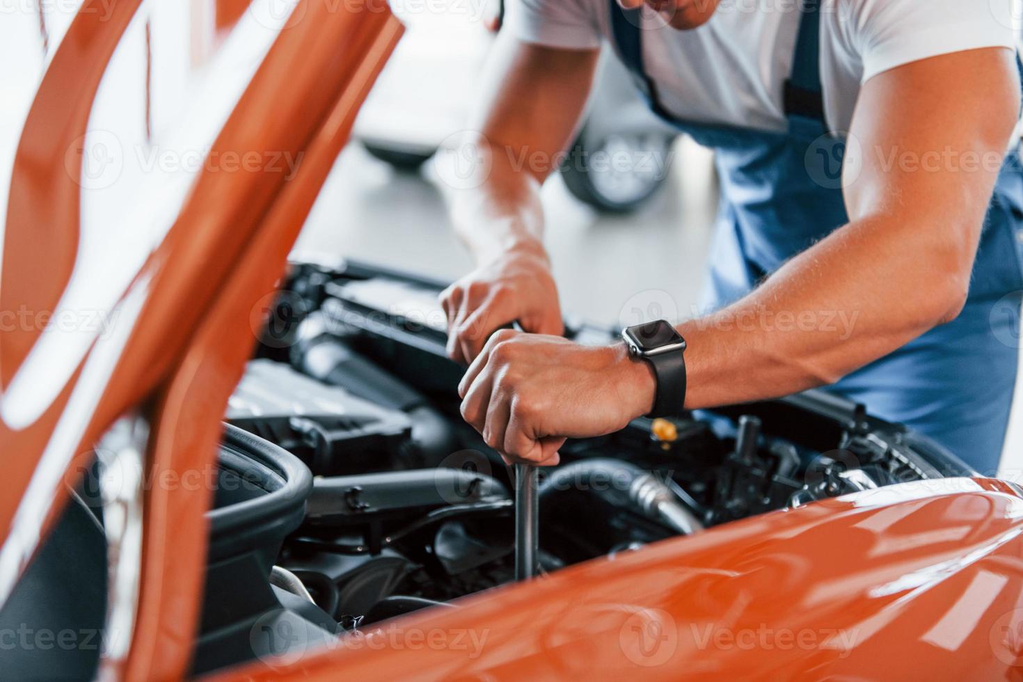 sotto il cappuccio. uomo nel uniforme è riparazione rotto automobile in casa foto