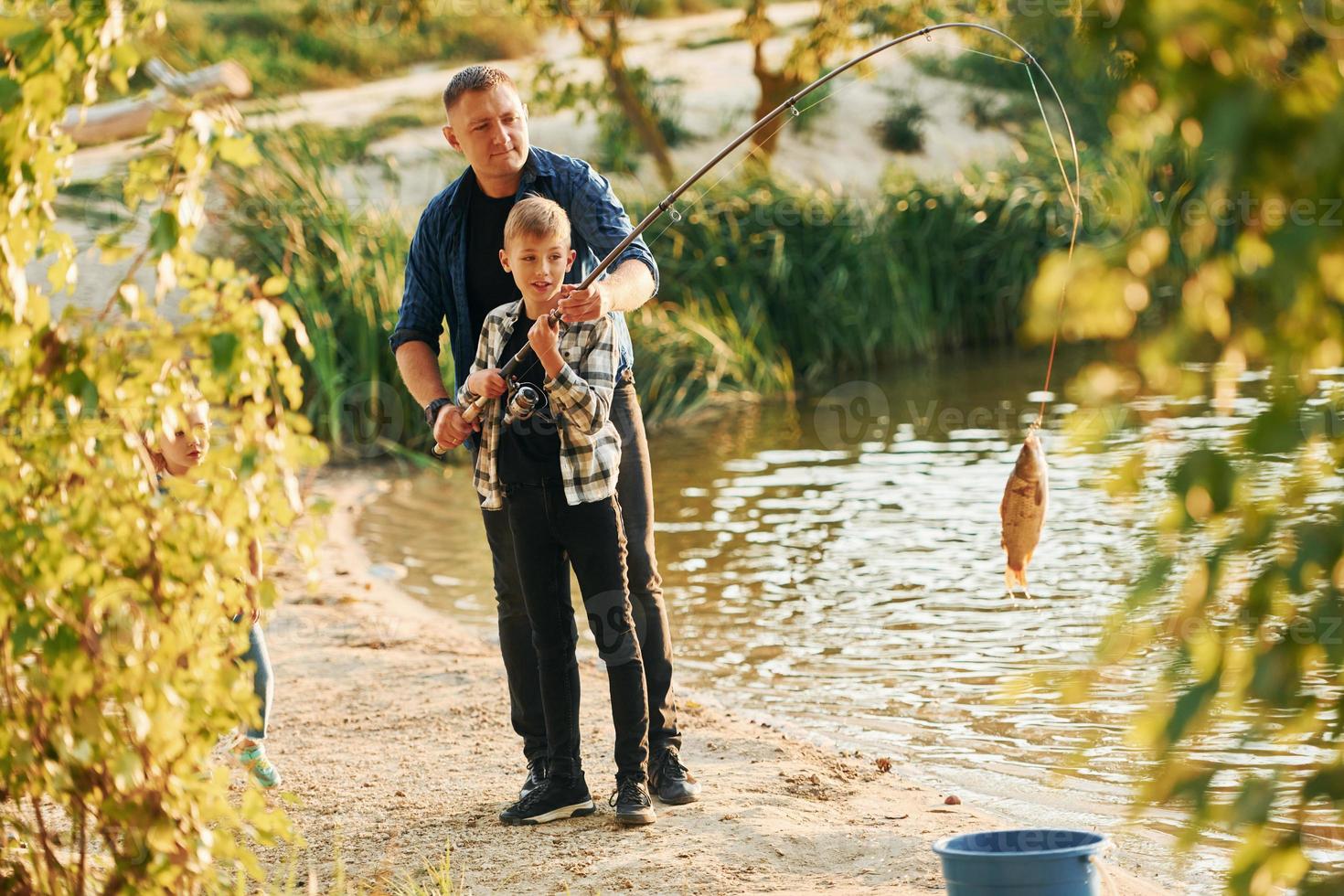 Tenere il presa. padre e figlio su pesca insieme all'aperto a estate foto