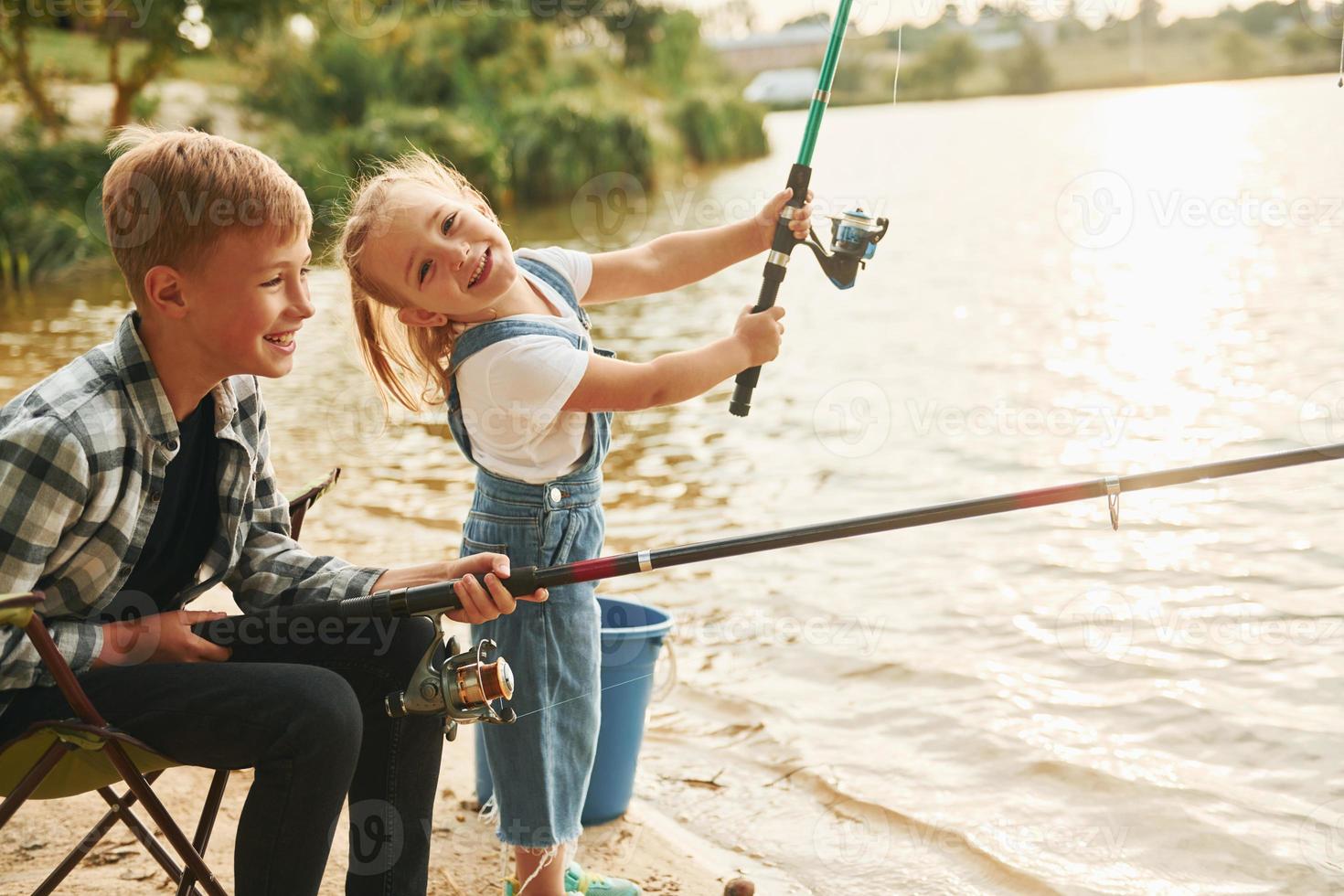 avendo divertimento. ragazzo con il suo sorella nel su pesca all'aperto a estate insieme foto