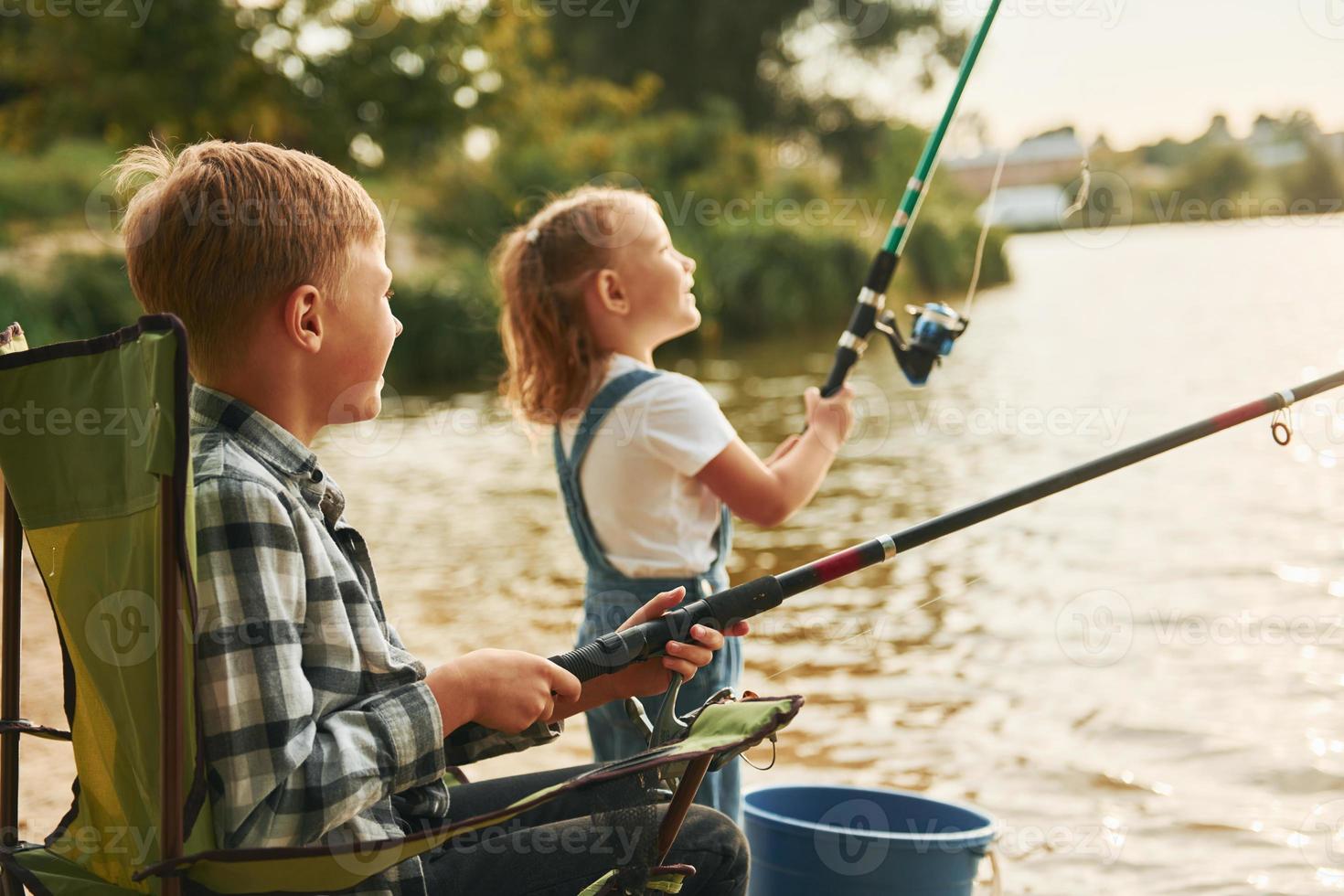 medio dimensioni lago. ragazzo con il suo sorella nel su pesca all'aperto a estate insieme foto