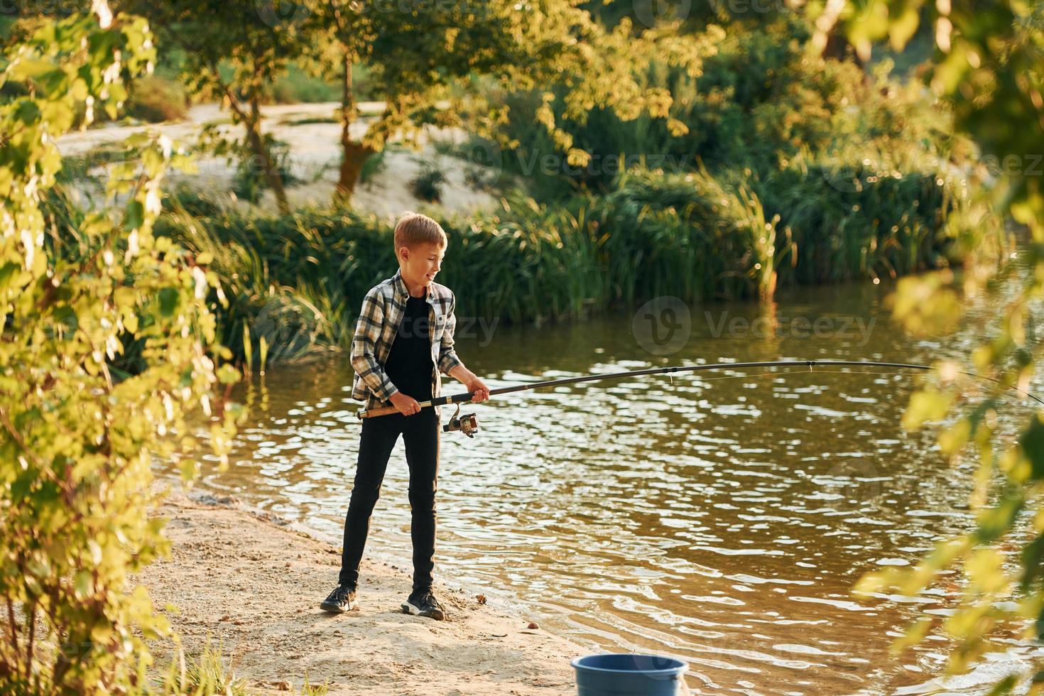 con bene presa. ragazzo nel casuale Abiti nel su pesca all'aperto a estate foto