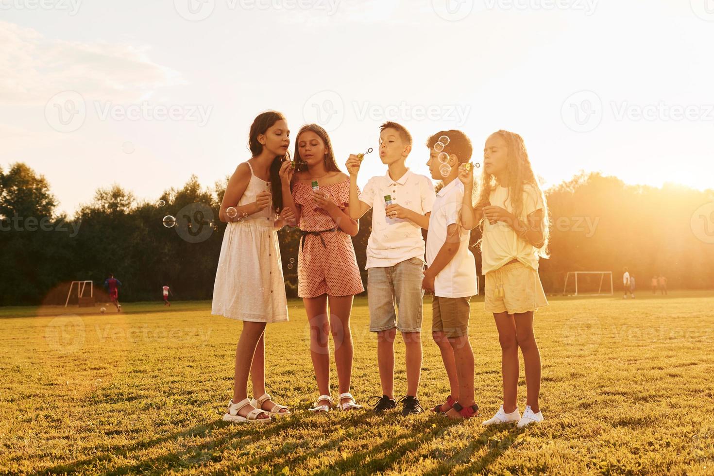 illuminato di luce del sole. in piedi su il allegro campo. gruppo di contento bambini è all'aperto a giorno foto