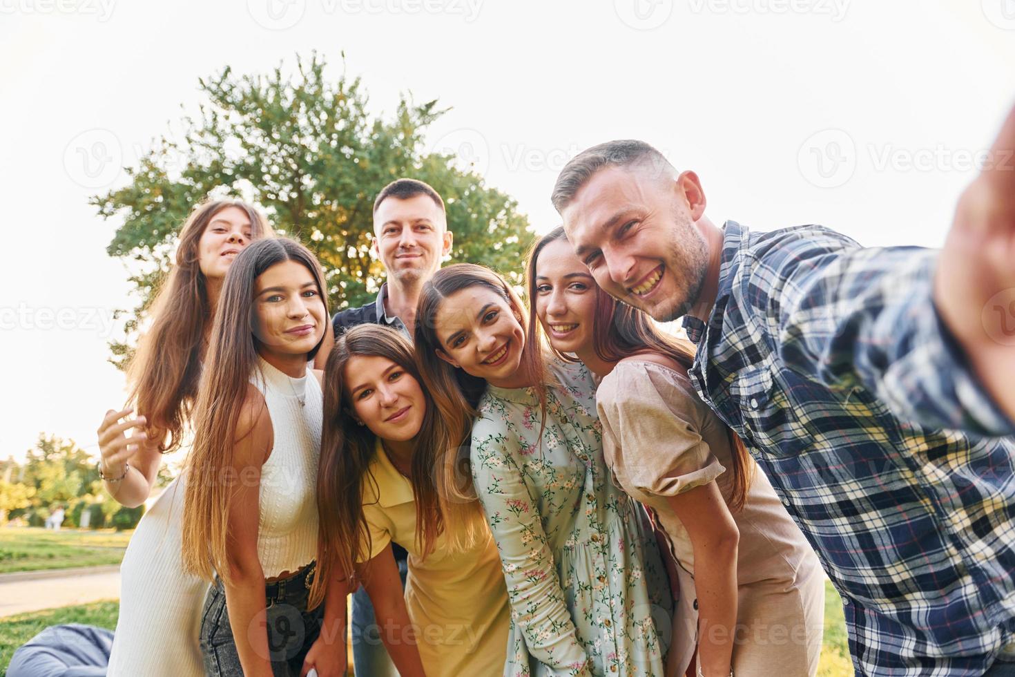 assunzione un' autoscatto. gruppo di giovane persone avere un' festa nel il parco a estate giorno foto