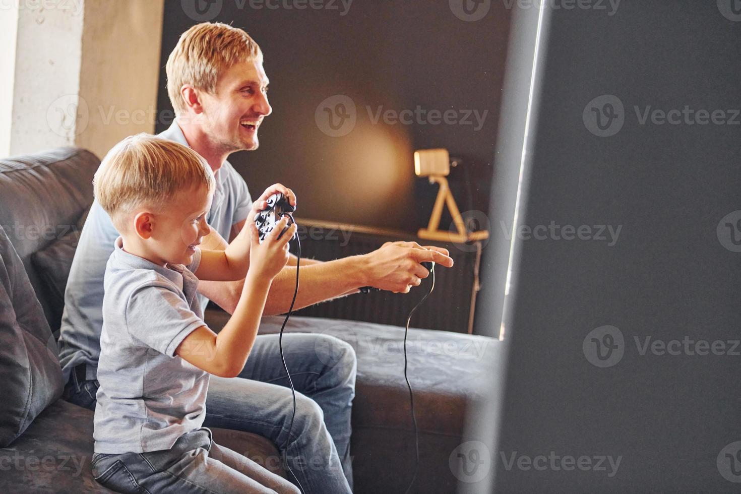 Tenere video gioco controllori. padre e figlio è in casa a casa insieme foto