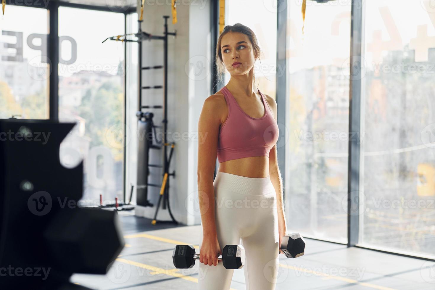 in piedi con attrezzatura. bellissimo giovane donna con sottile corpo genere è nel il Palestra foto