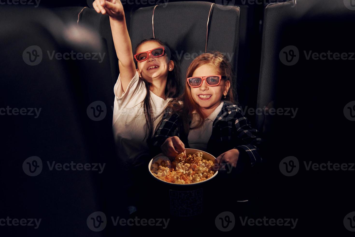 Due bambini seduta nel cinema e Guardando film insieme foto