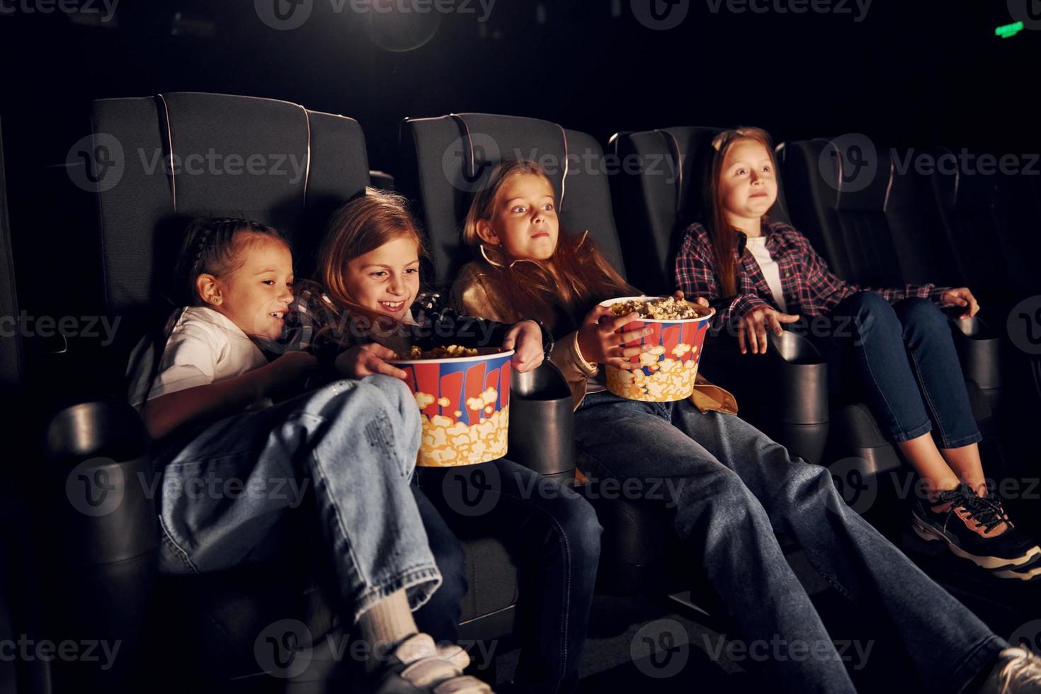 seduta su il nero sedili. gruppo di bambini seduta nel cinema e Guardando film insieme foto