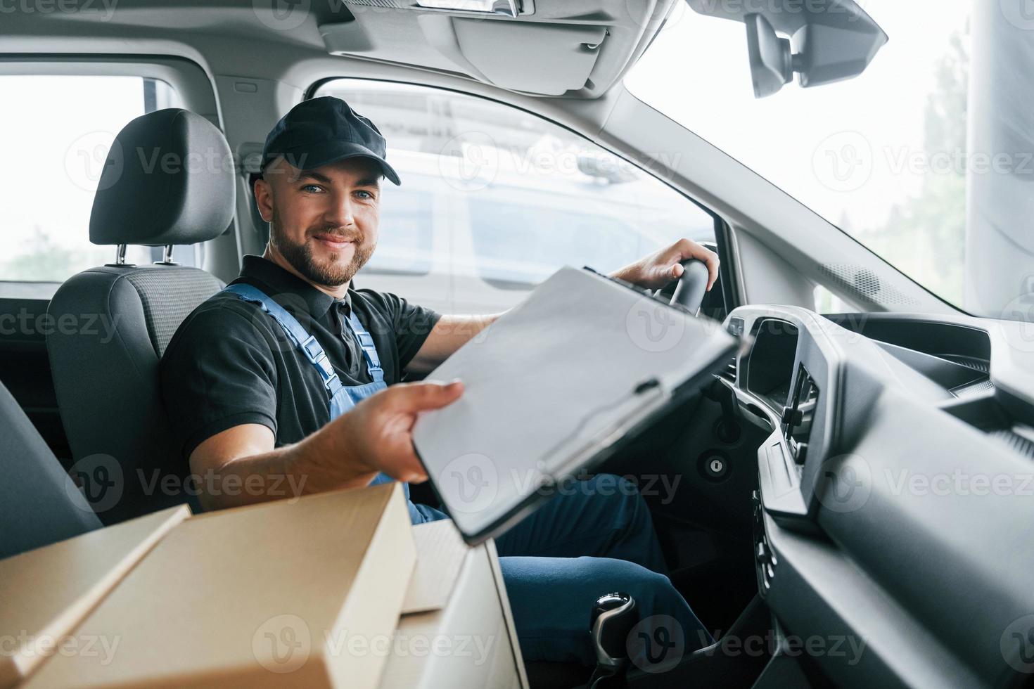 con documento. consegna uomo nel uniforme è in casa con auto e con ordine foto