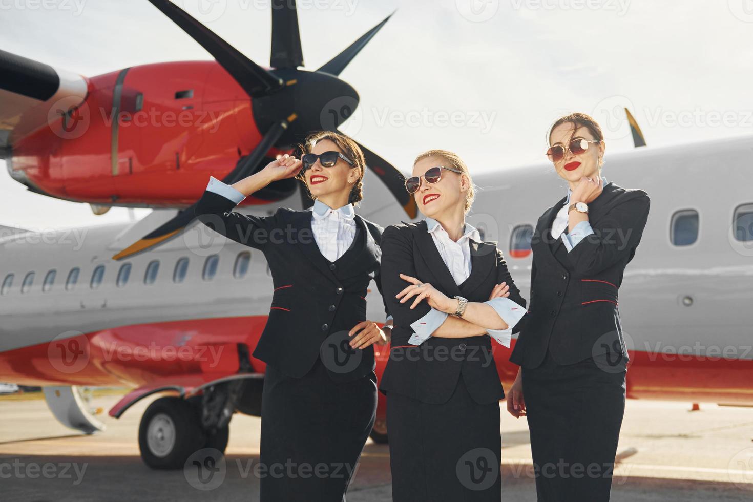 tre hostess. equipaggio di aeroporto e aereo lavoratori nel formale Abiti in piedi all'aperto insieme foto