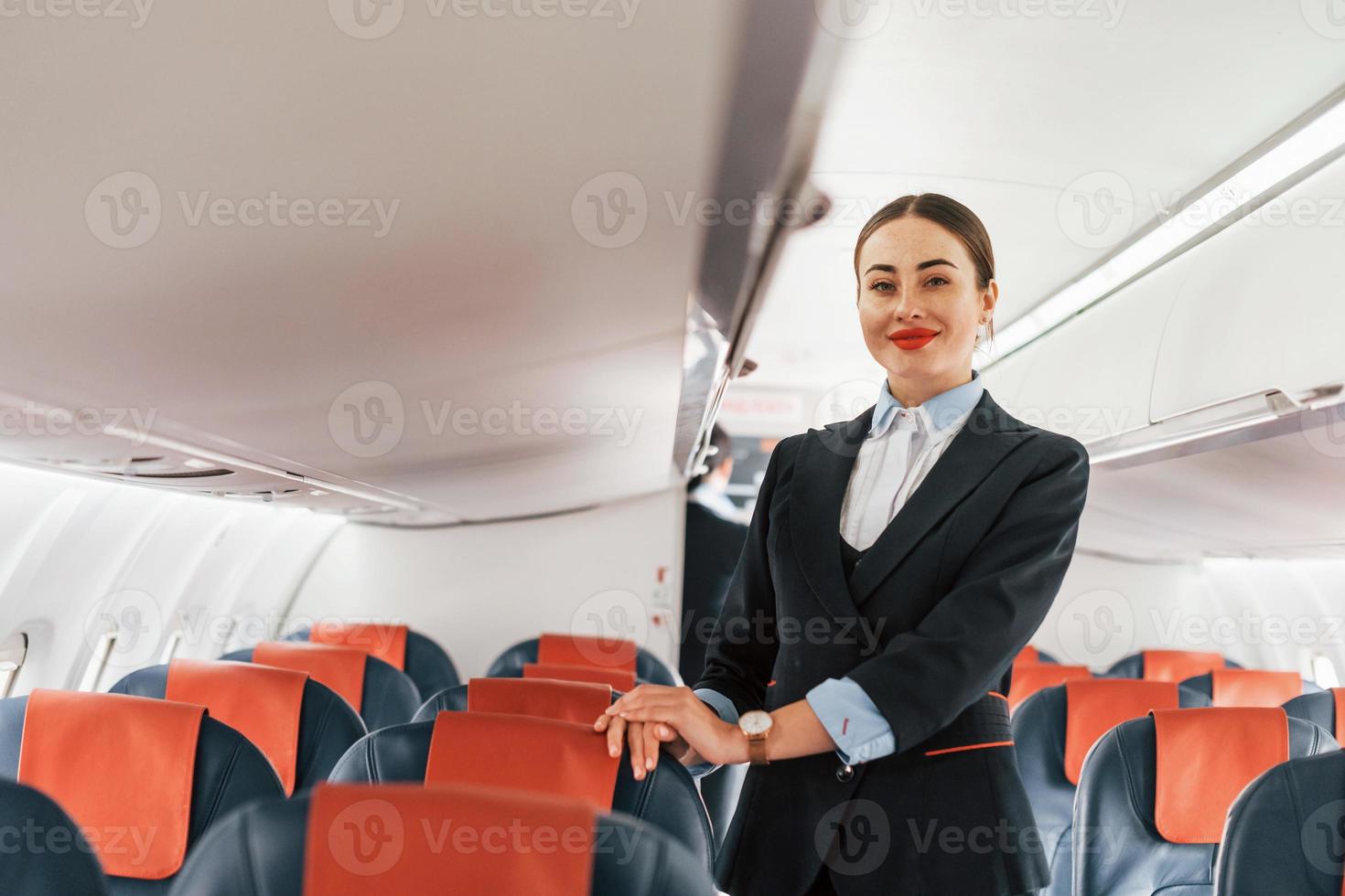 giovane hostess quello è nel formale nero Abiti è in piedi in casa nel il aereo foto