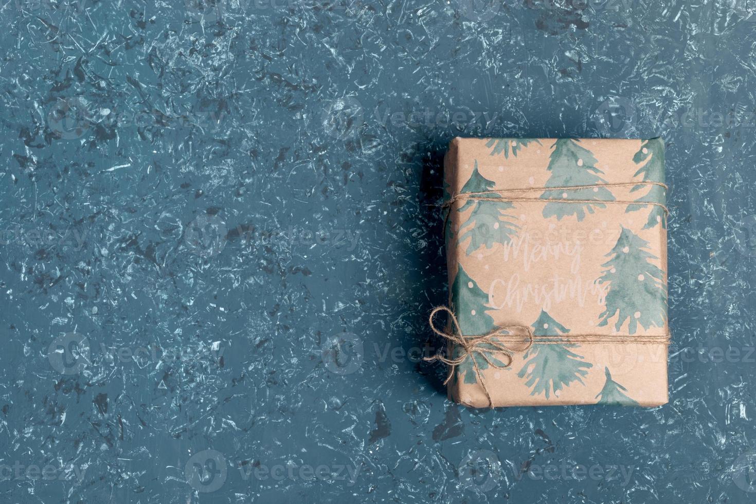 uno regalo scatola avvolto nel festivo natale involucro carta su turchese strutturato sfondo. superiore Visualizza. copia spazio. foto