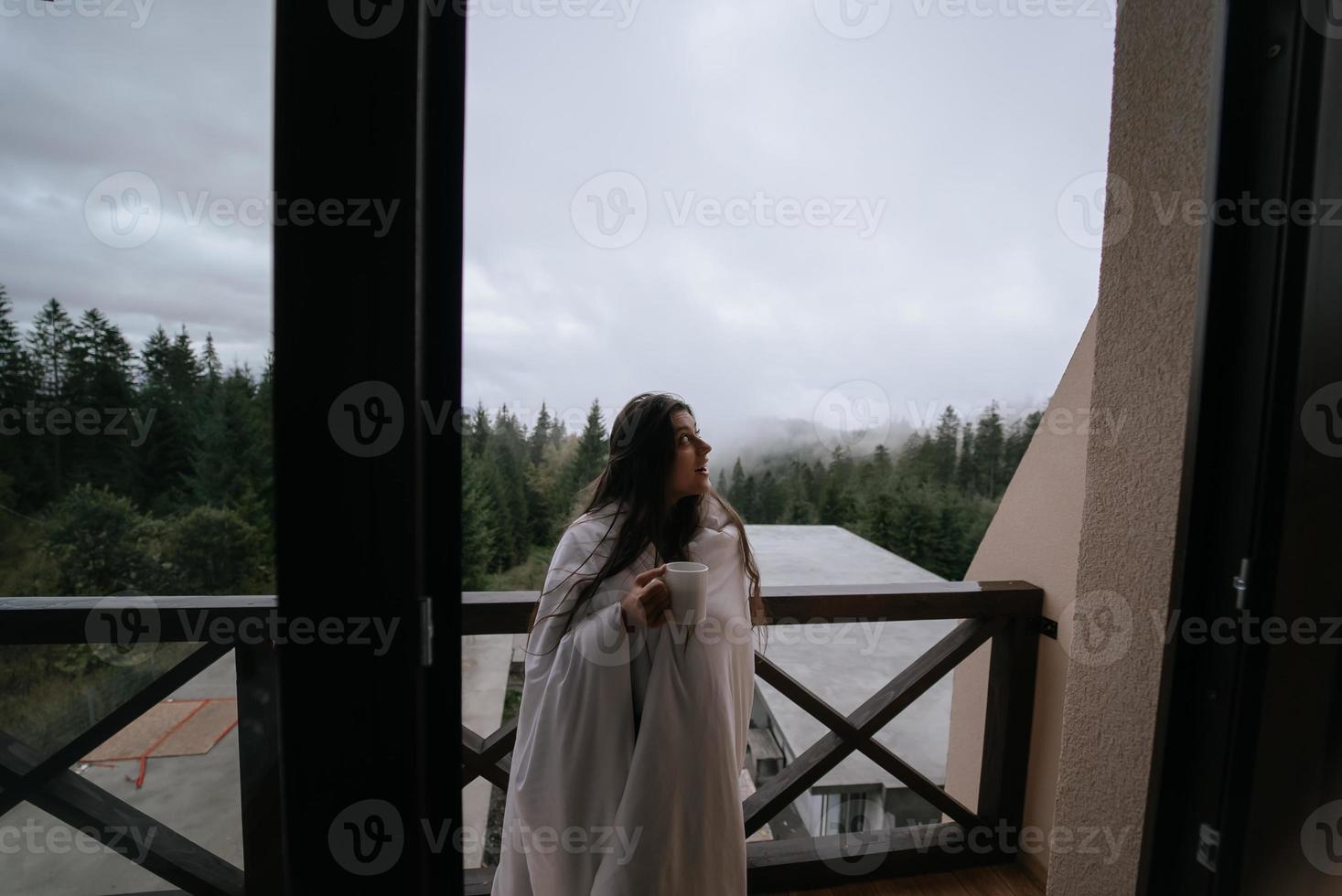 donna potabile tè su accogliente balcone di un' nazione Casa. foto