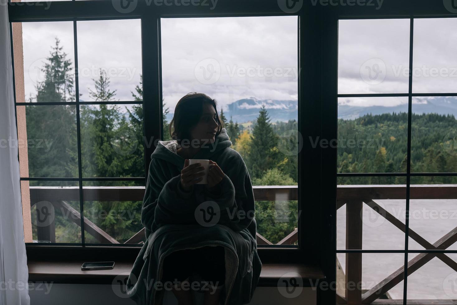 silhouette di un' donna seduta su il davanzale con un' boccale foto