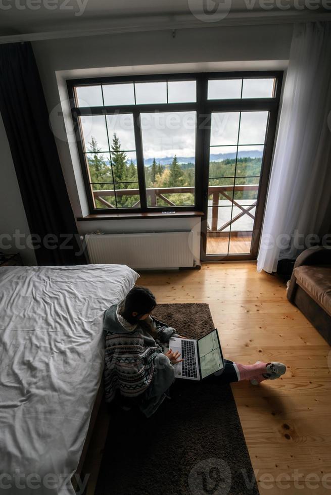 femmina con il computer portatile seduta su il pavimento e Lavorando su il computer portatile foto