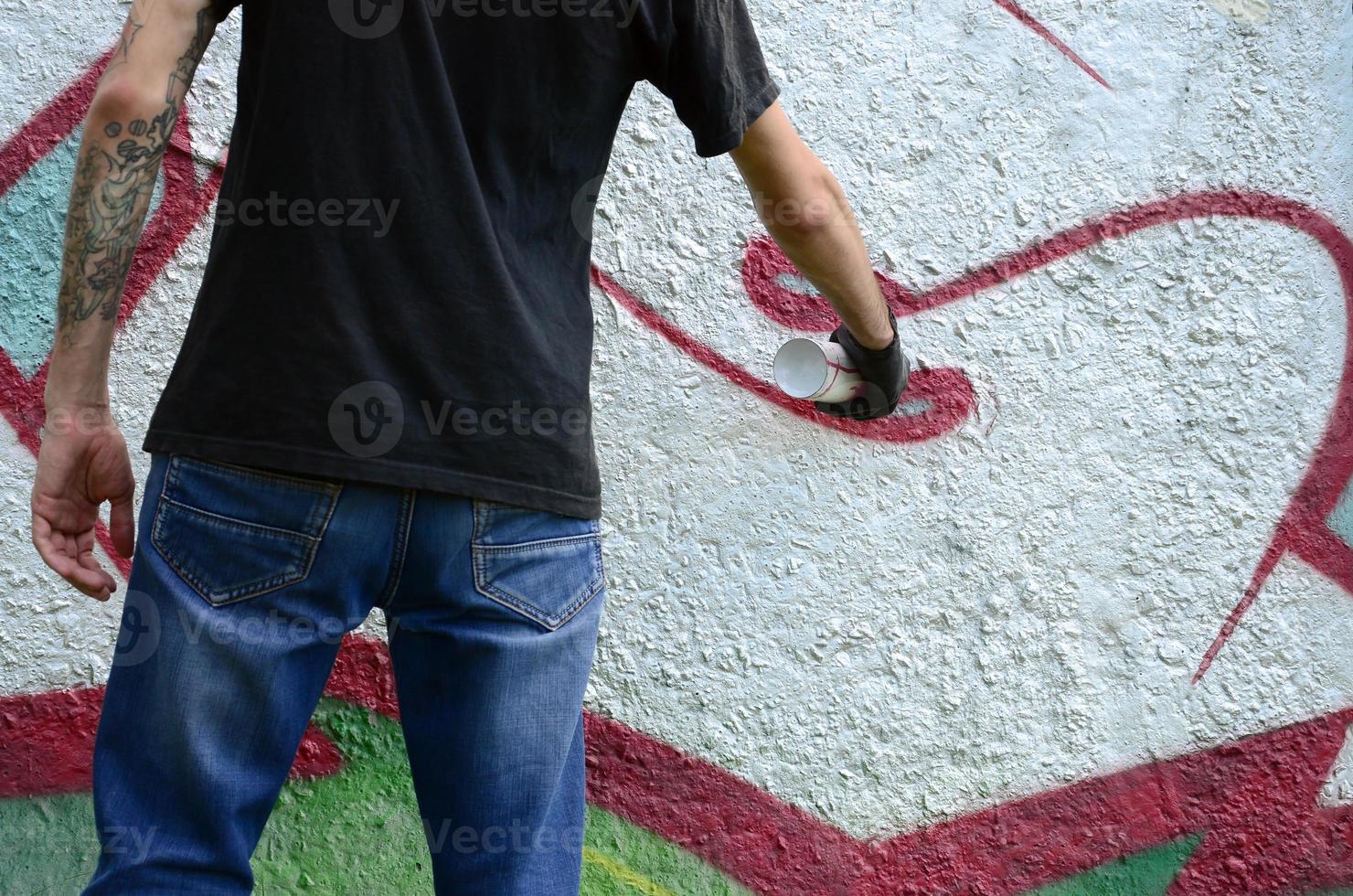 un' giovane teppista vernici graffiti su un' calcestruzzo parete. illegale vandalismo concetto. strada arte foto