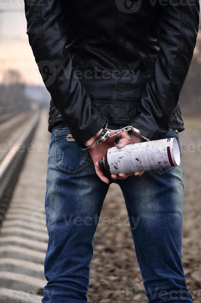 ragazza nel manette con bombola spray su il sfondo di un' ferrovia traccia. il concetto di vandalismo prevenzione con il partecipazione di il ferrovia e treni. foto