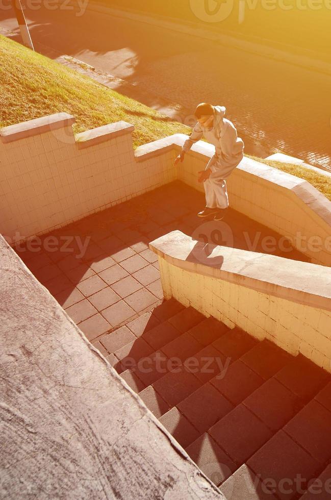 un' giovane tipo esegue un' saltare attraverso il spazio fra il calcestruzzo parapetti. il atleta pratiche parkour, formazione nel strada condizioni. il concetto di gli sport sottoculture tra gioventù foto