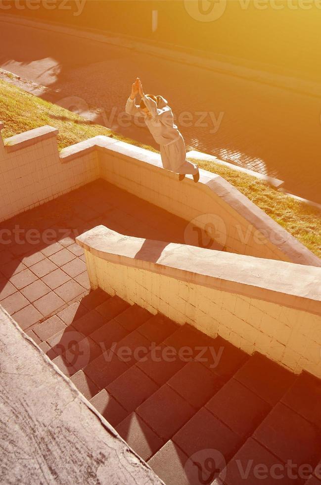 un' giovane tipo esegue un' saltare attraverso il spazio fra il calcestruzzo parapetti. il atleta pratiche parkour, formazione nel strada condizioni. il concetto di gli sport sottoculture tra gioventù foto