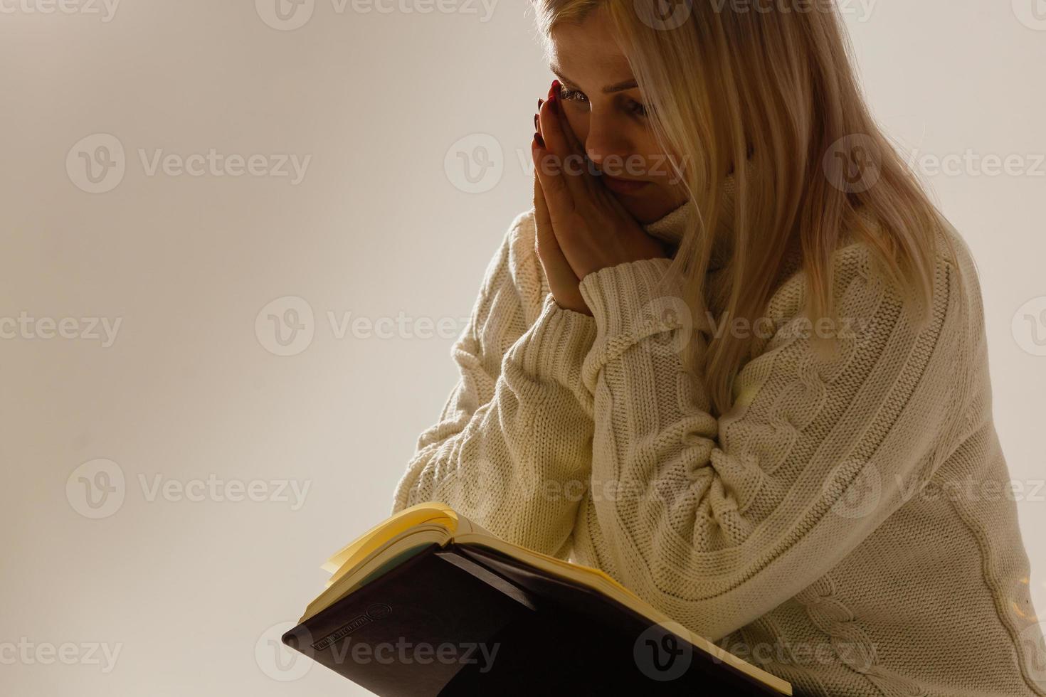 un' giovane donna nel preghiera sotto drammatico luce. foto