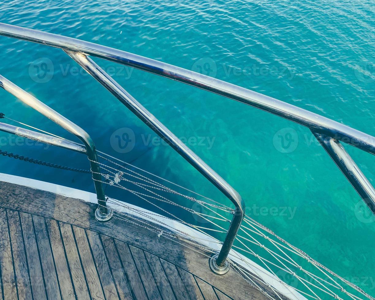 yacht nel il Aperto mare. mare con un' sabbioso spiaggia contro il fondale di un' montagna. per proteggere turisti a partire dal cadente, Là è un' tavola fatto di legna con metallo corrimano foto